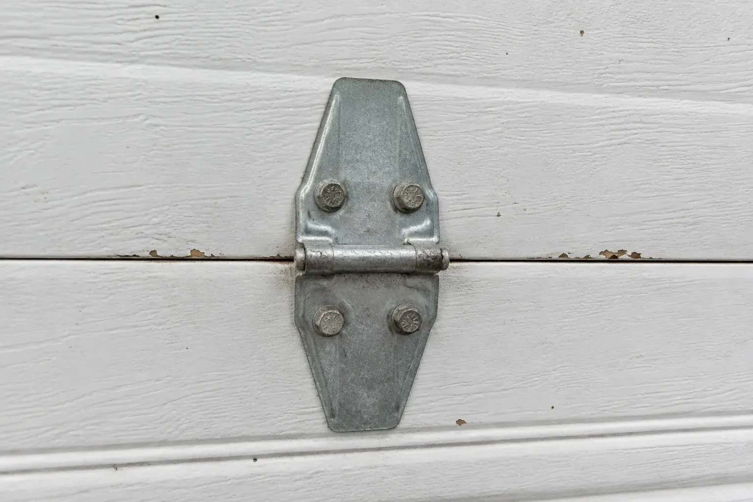 Metal center hinge across a seam in a white sectional garage door. — Garage Door Hinge Replacement, Georgina